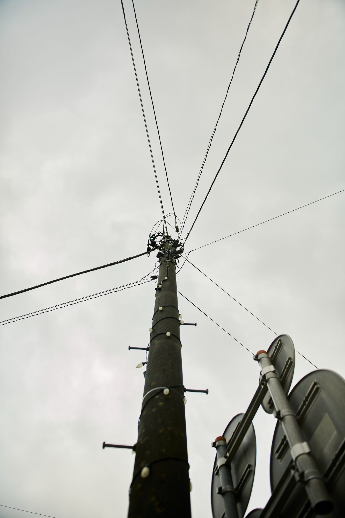 A utility pole with power lines fanning out against an overcast sky