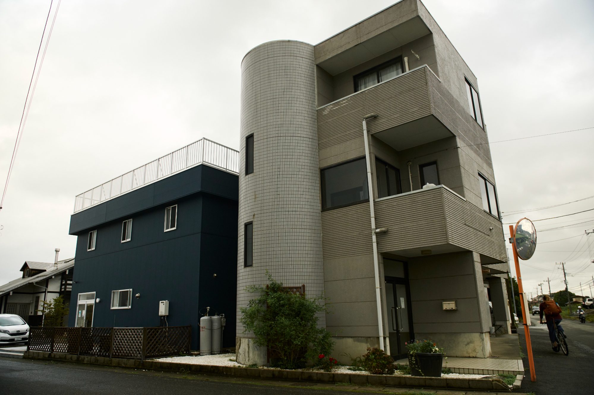 A dark blue building with a round corner tower on a quiet street
