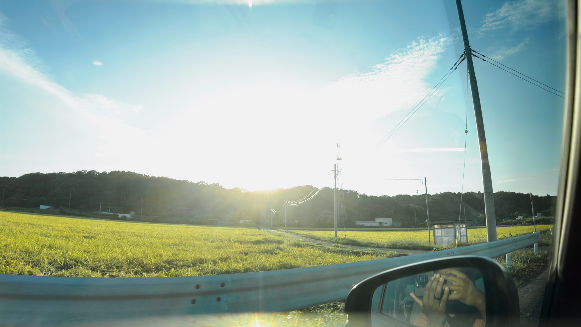 Late sun over green fields, photographed from a car window