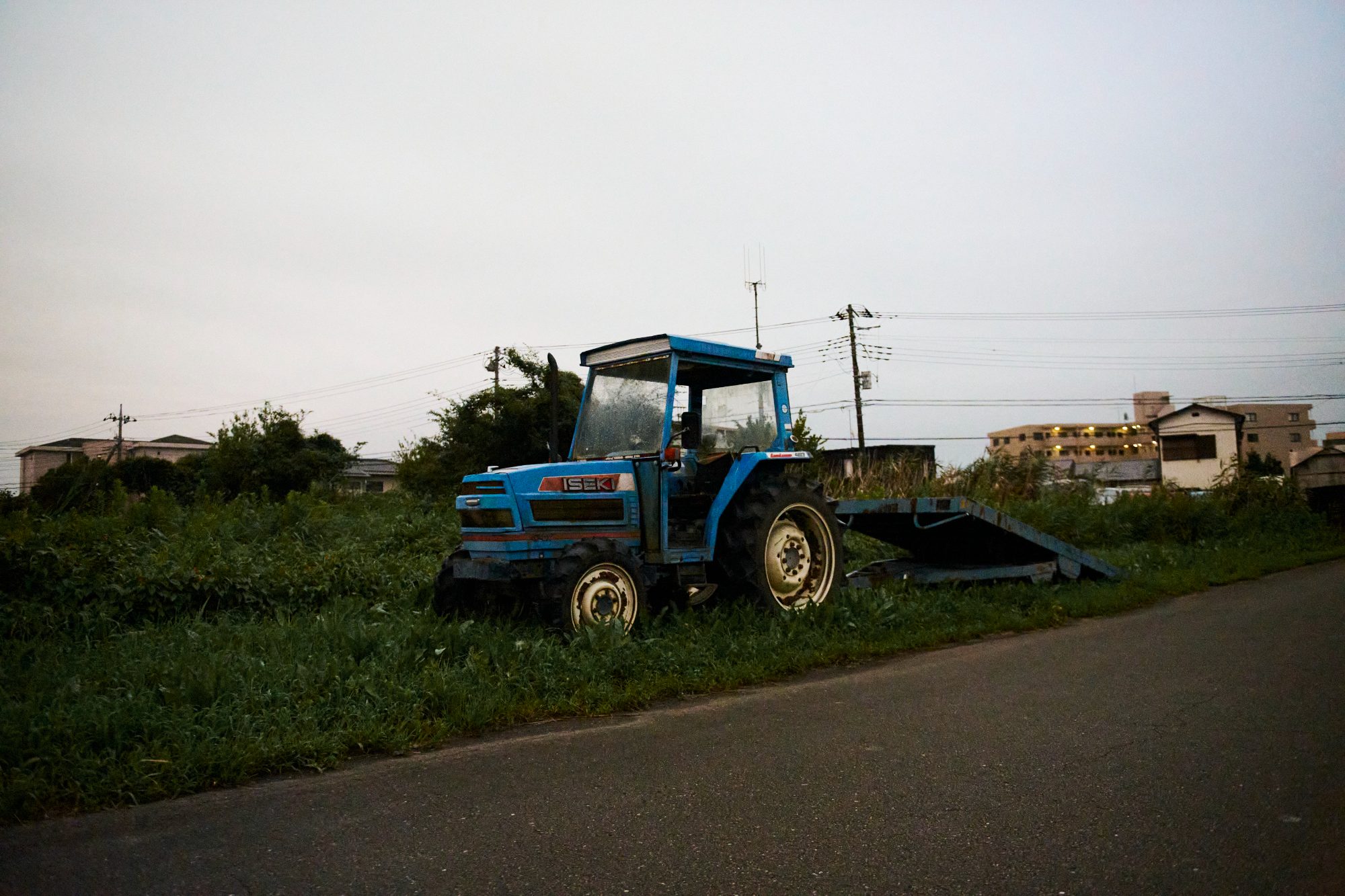 A blue tractor parked beside a field road