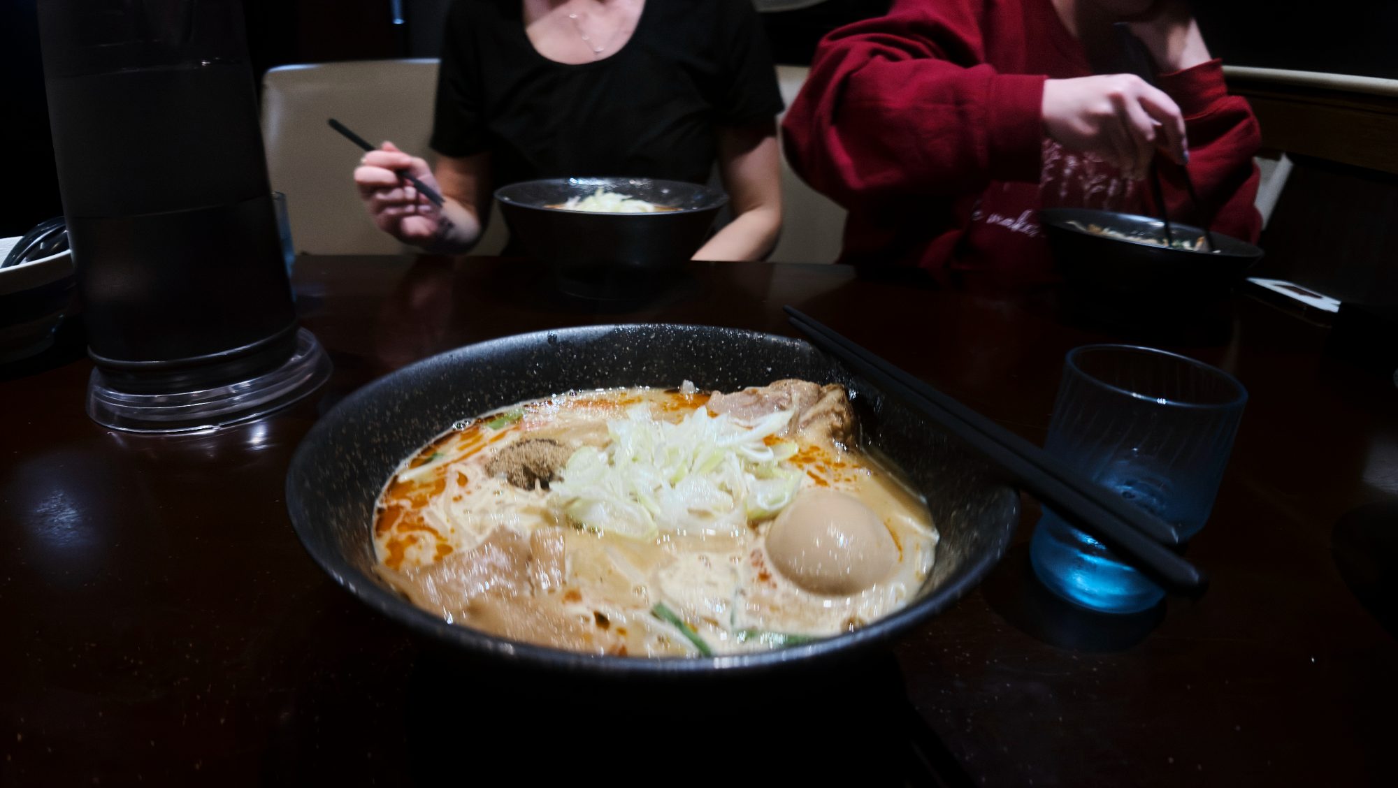A bowl of ramen with a soft-boiled egg on a dark table