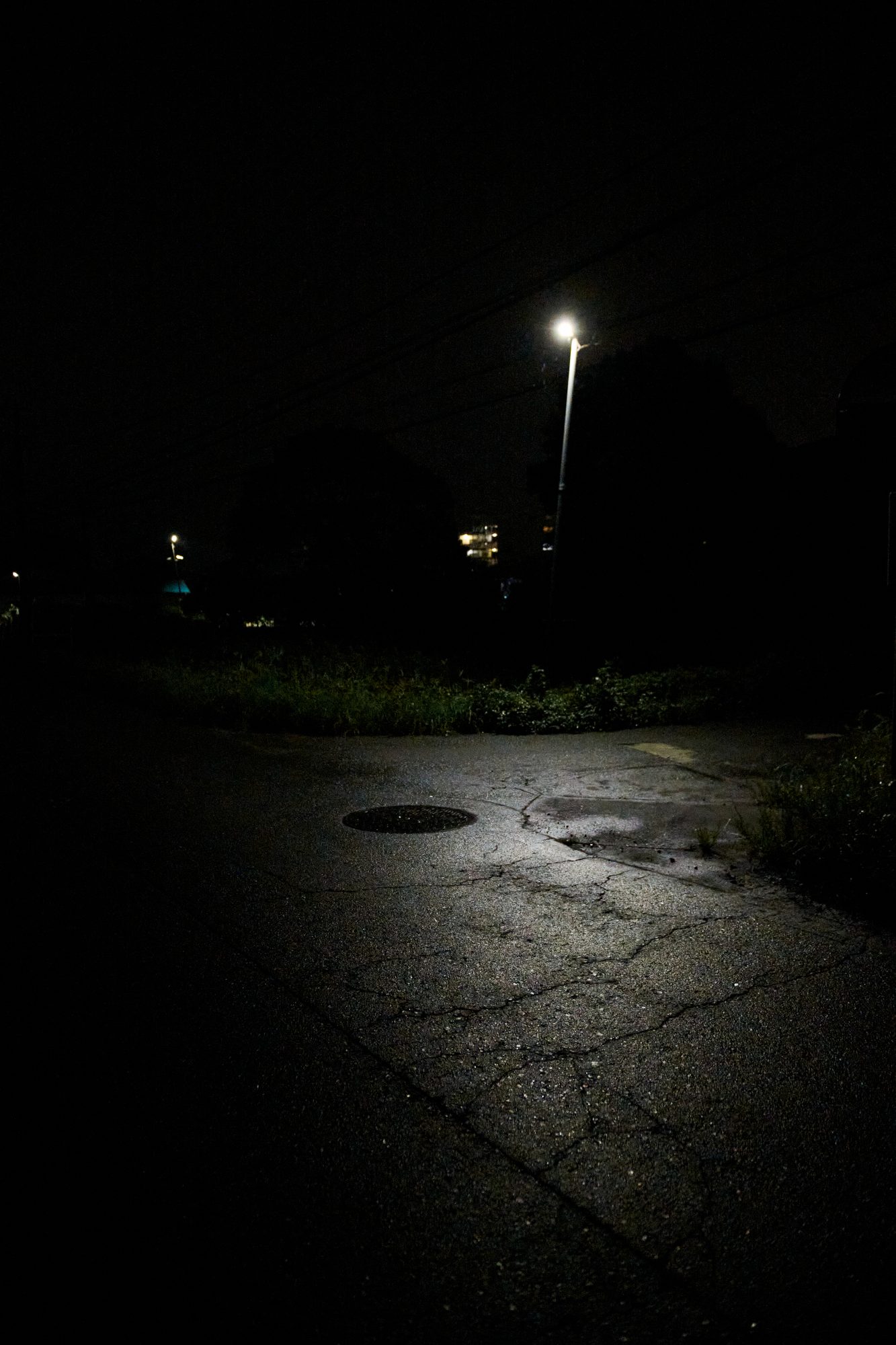 A single streetlight over an empty wet parking lot at night
