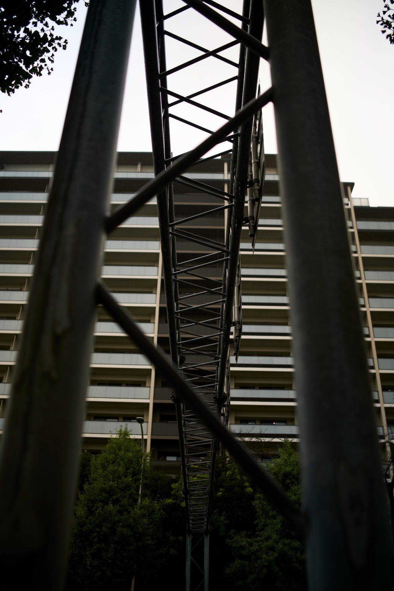 A steel lattice tower rising in front of a long apartment block