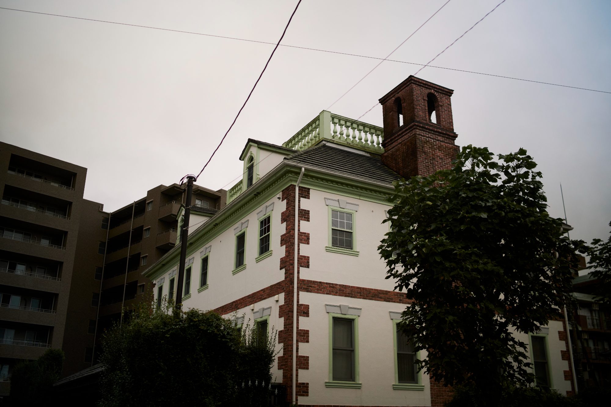 A red brick building with a bell tower among trees
