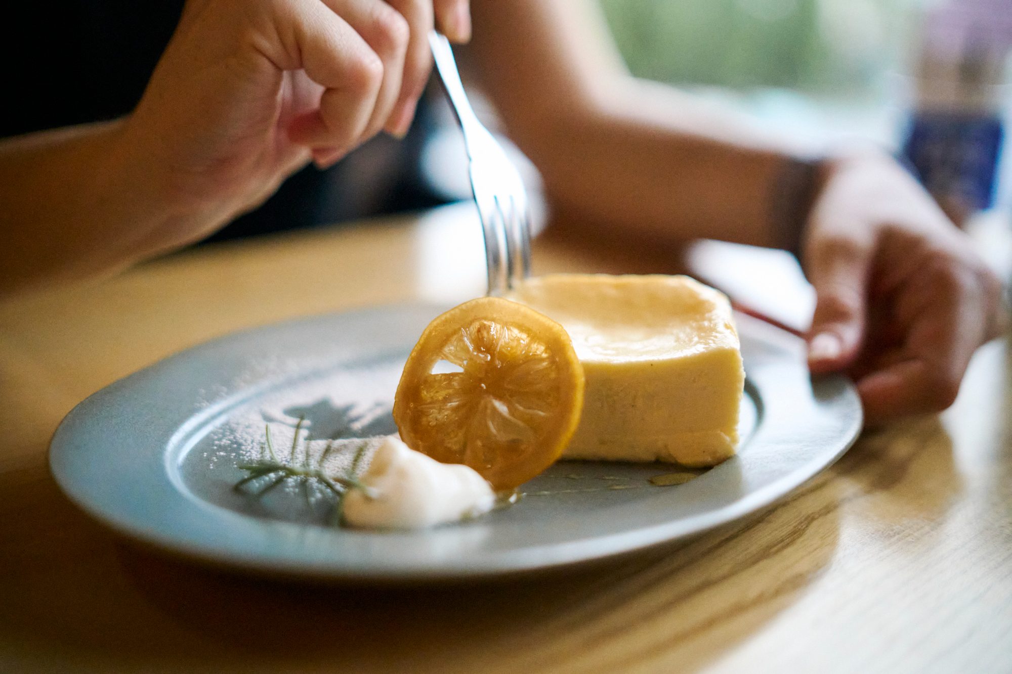 A fork cutting into a slice of cheesecake with a candied lemon on top