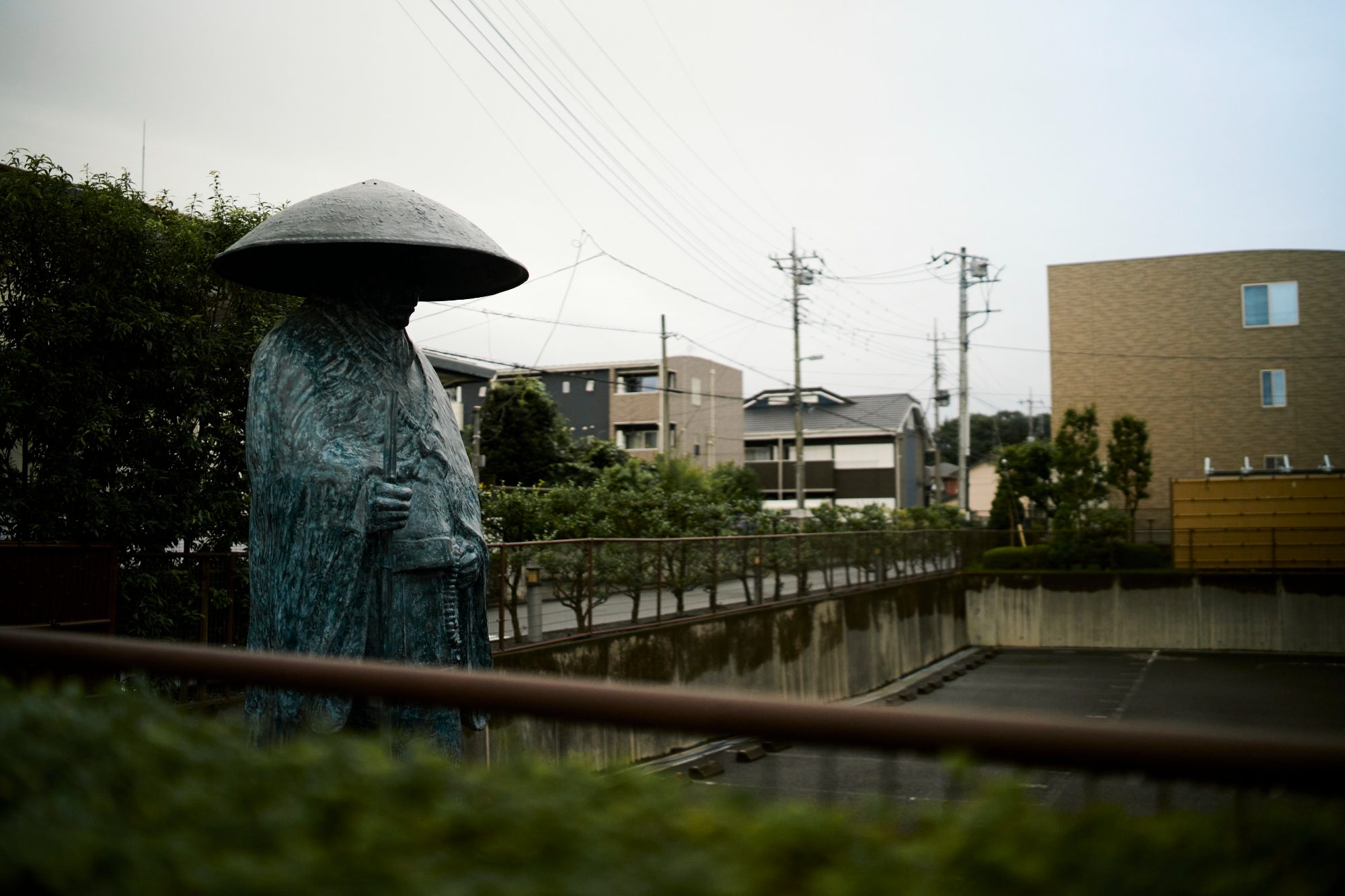 A small stone statue in a straw hat beside a canal