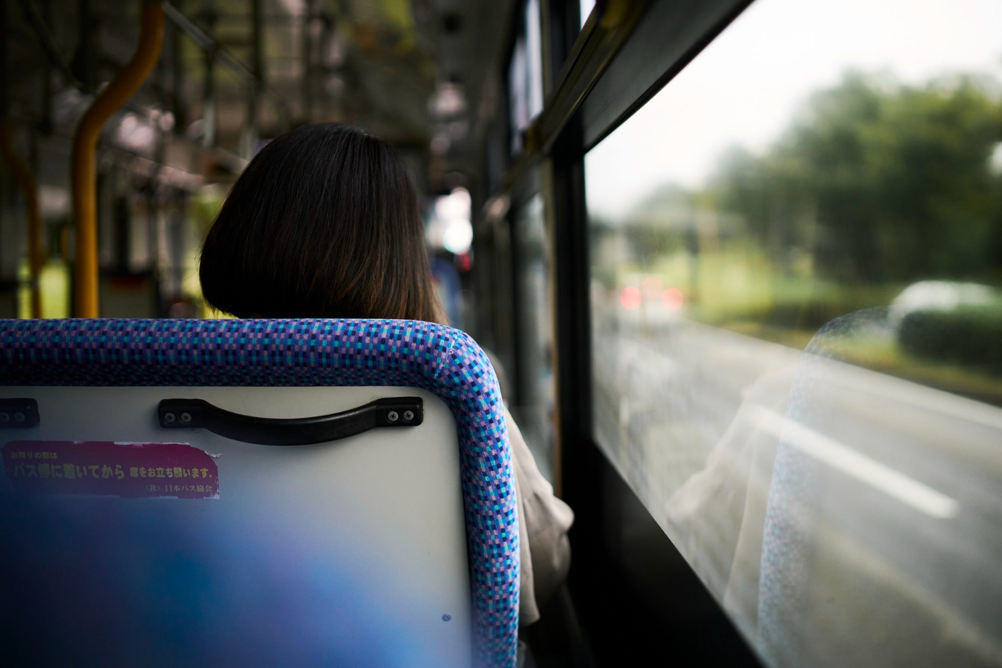 Looking out the window of a city bus at trees passing by