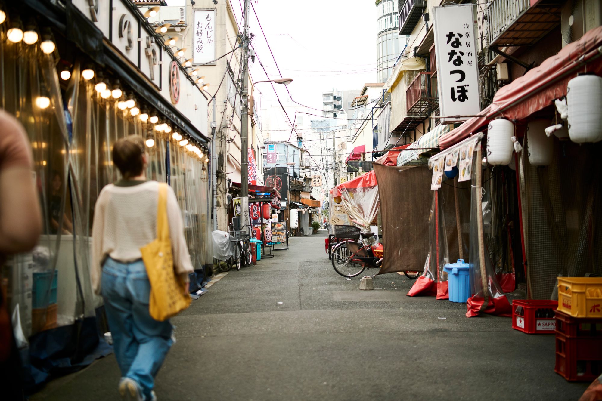 A covered market street, a shopper in white walking past