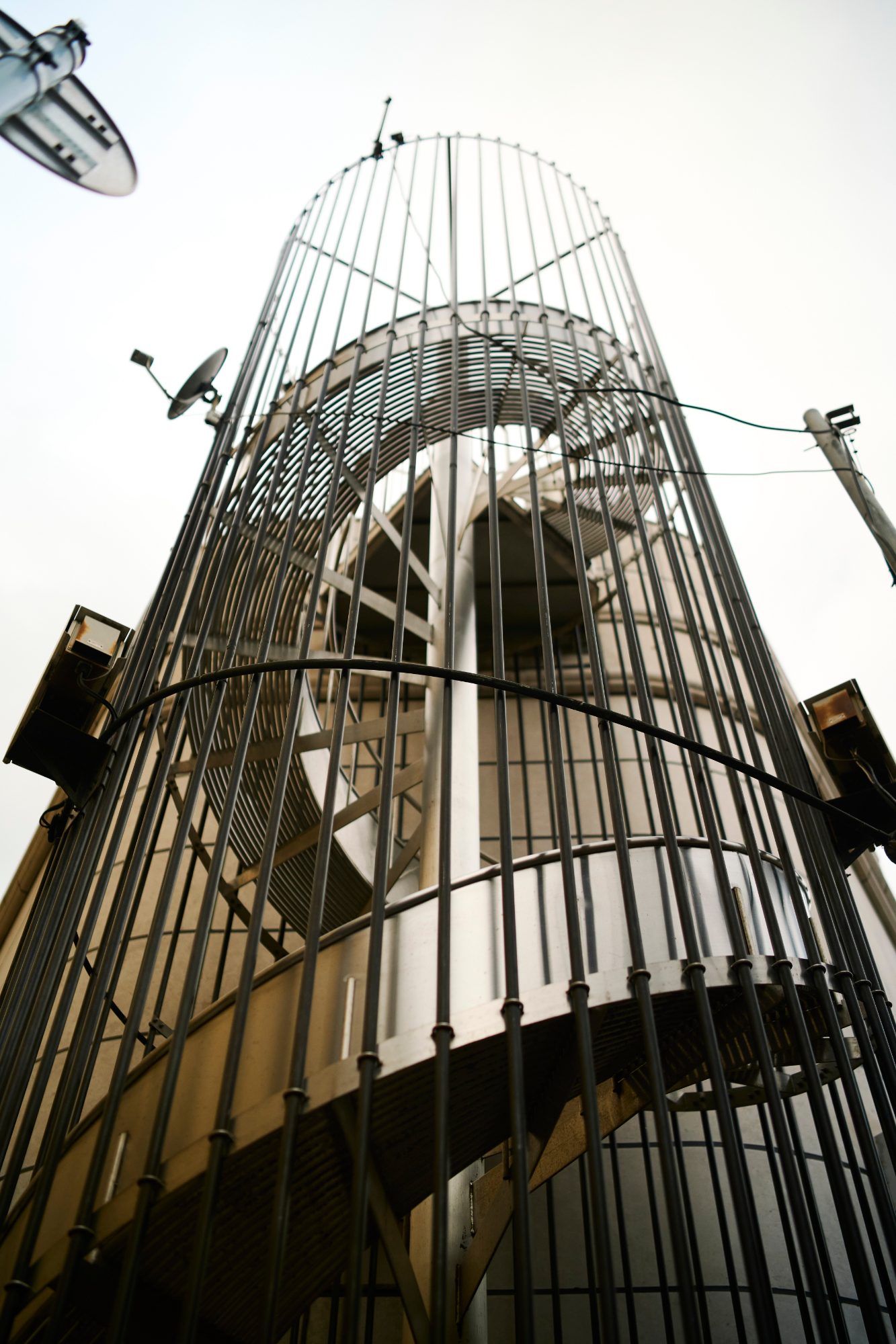 A caged spiral staircase rising up a building