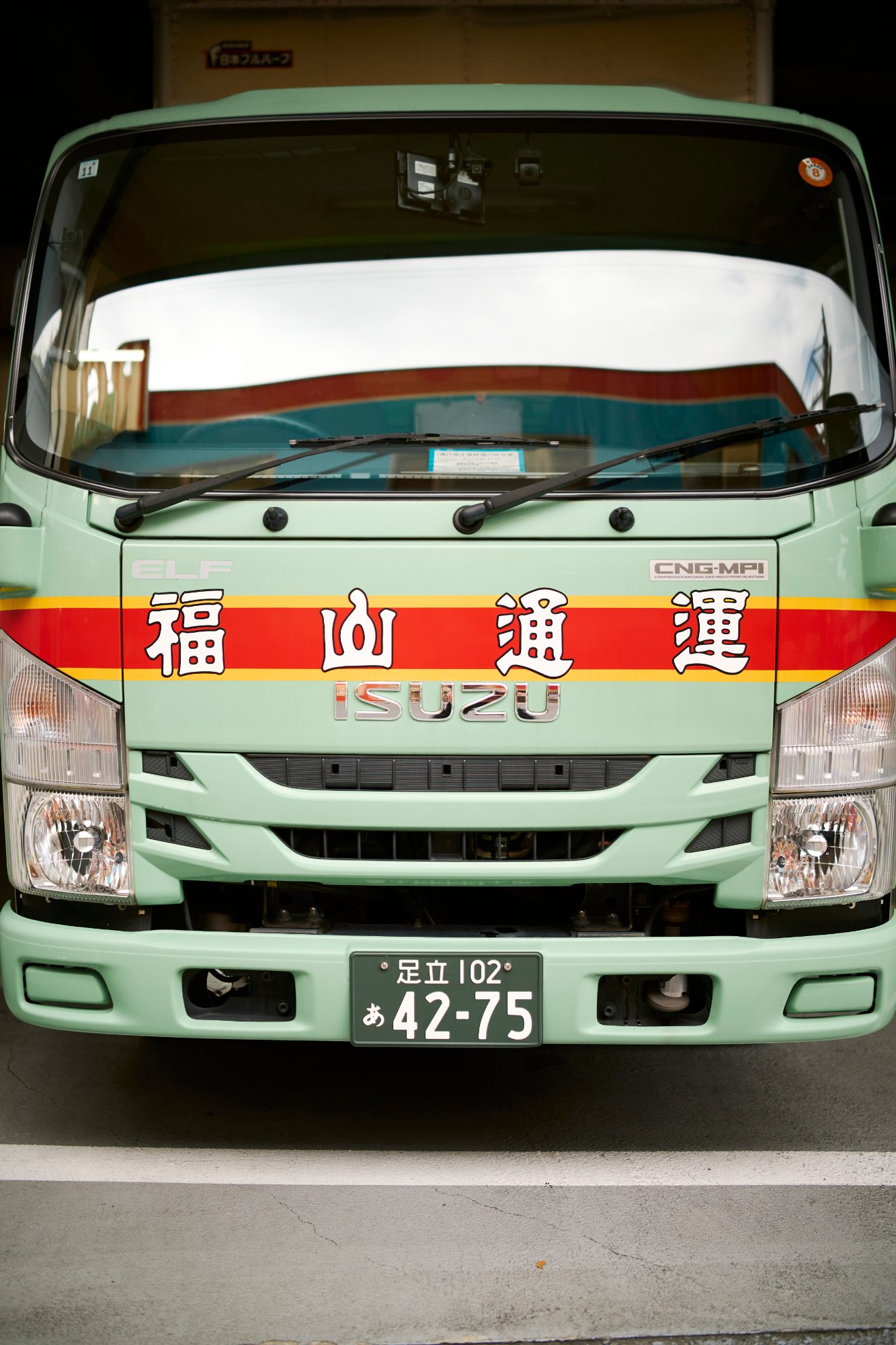 The front of a pale green delivery truck