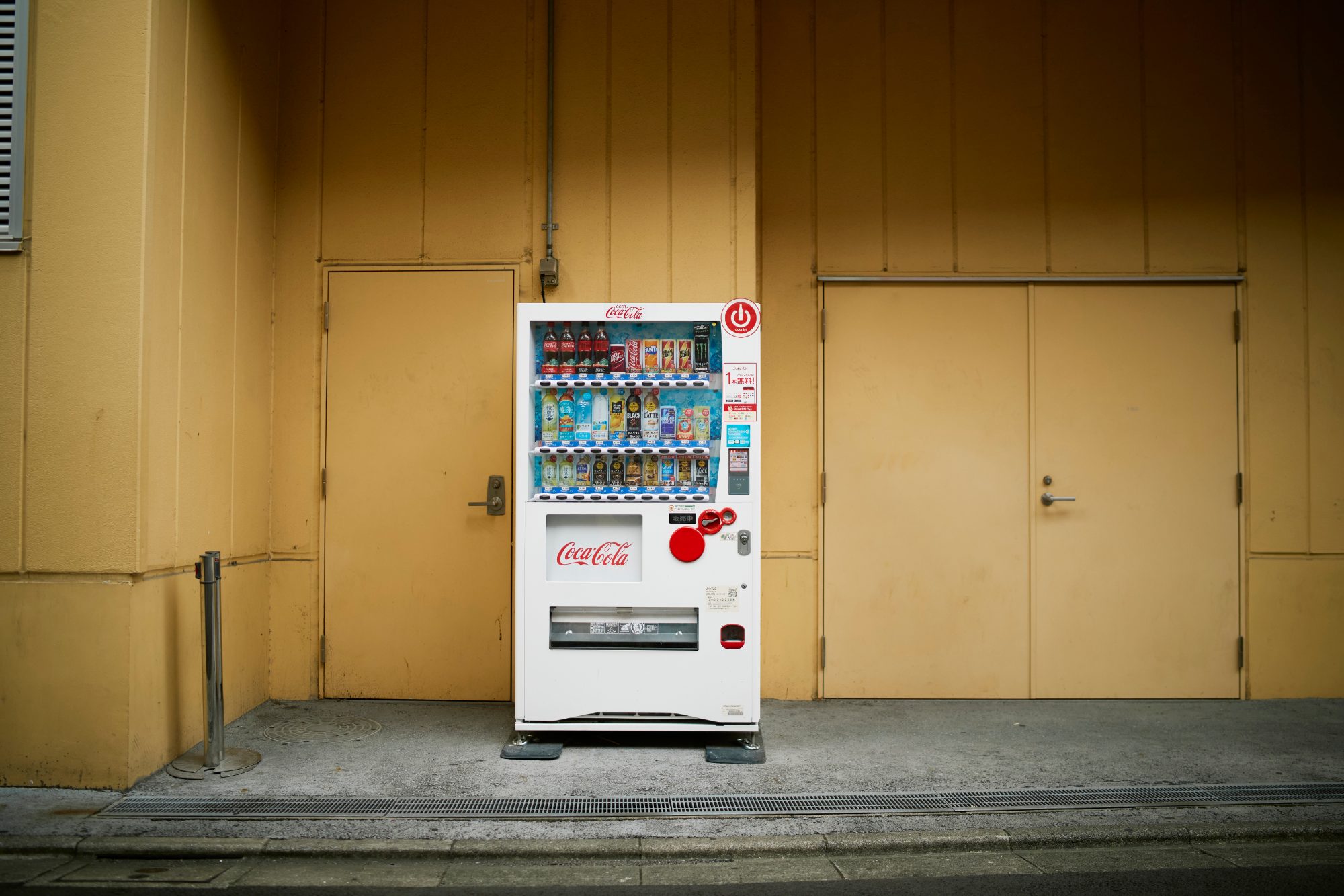 A lone vending machine against a mustard-yellow wall