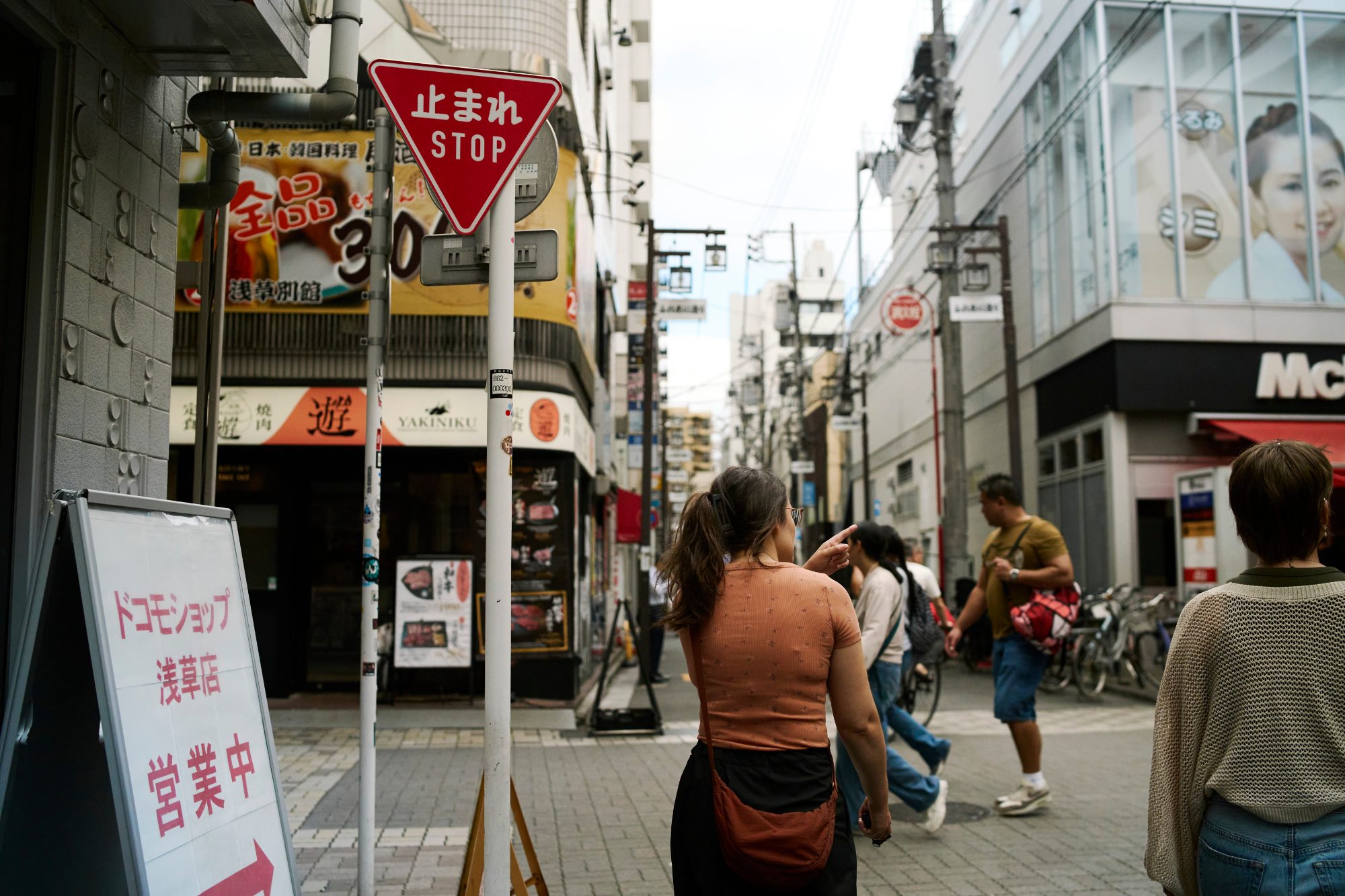 Pedestrians at a busy street corner beneath a stop sign