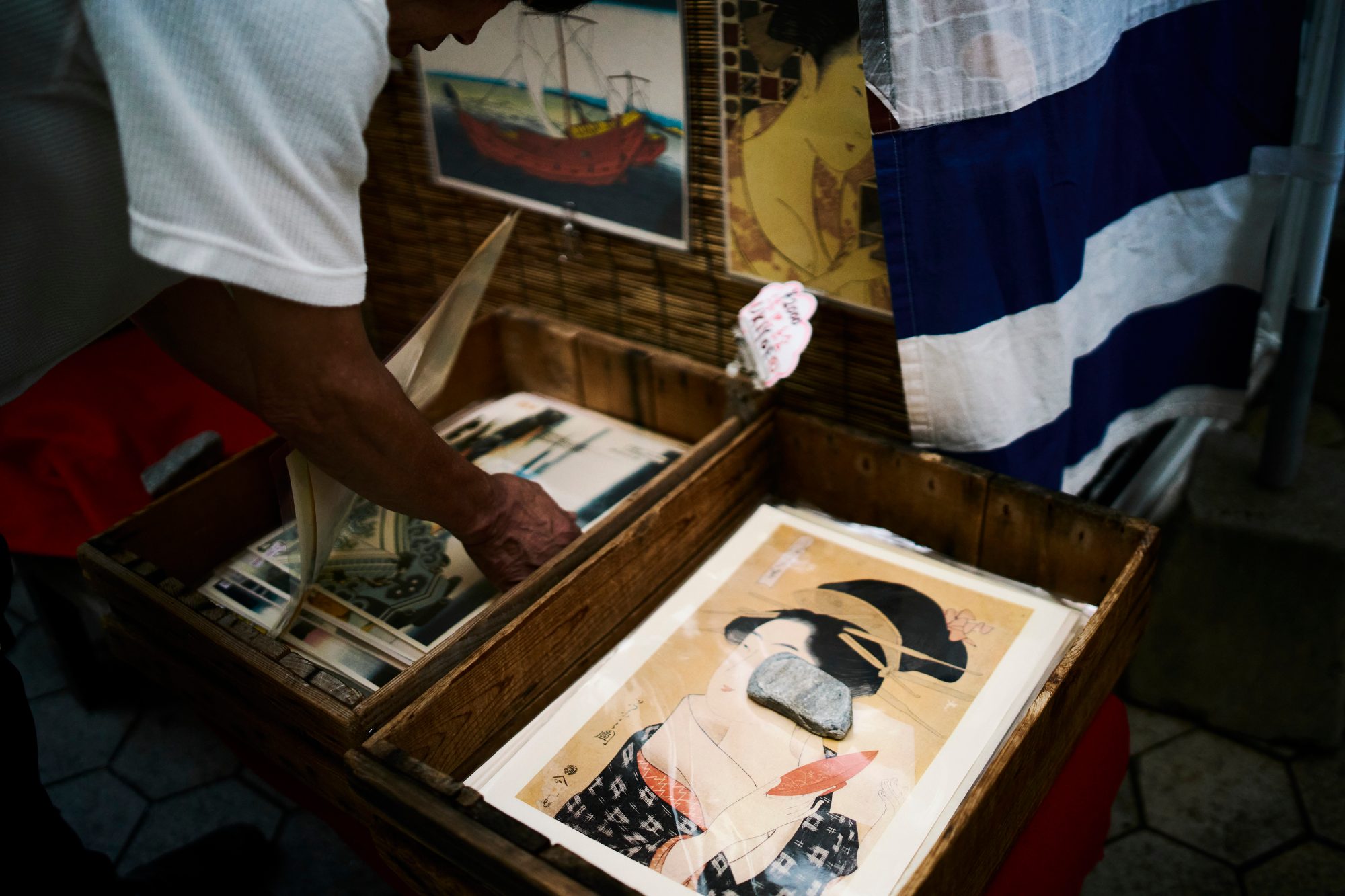 A vendor showing woodblock prints from a wooden case