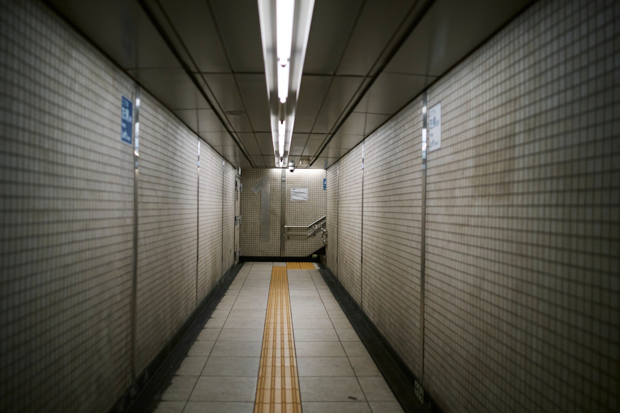 A tiled subway passage with a yellow tactile strip