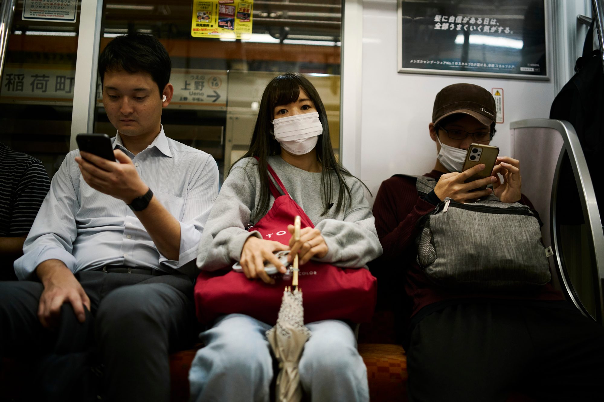 Passengers on a train, each looking at a phone