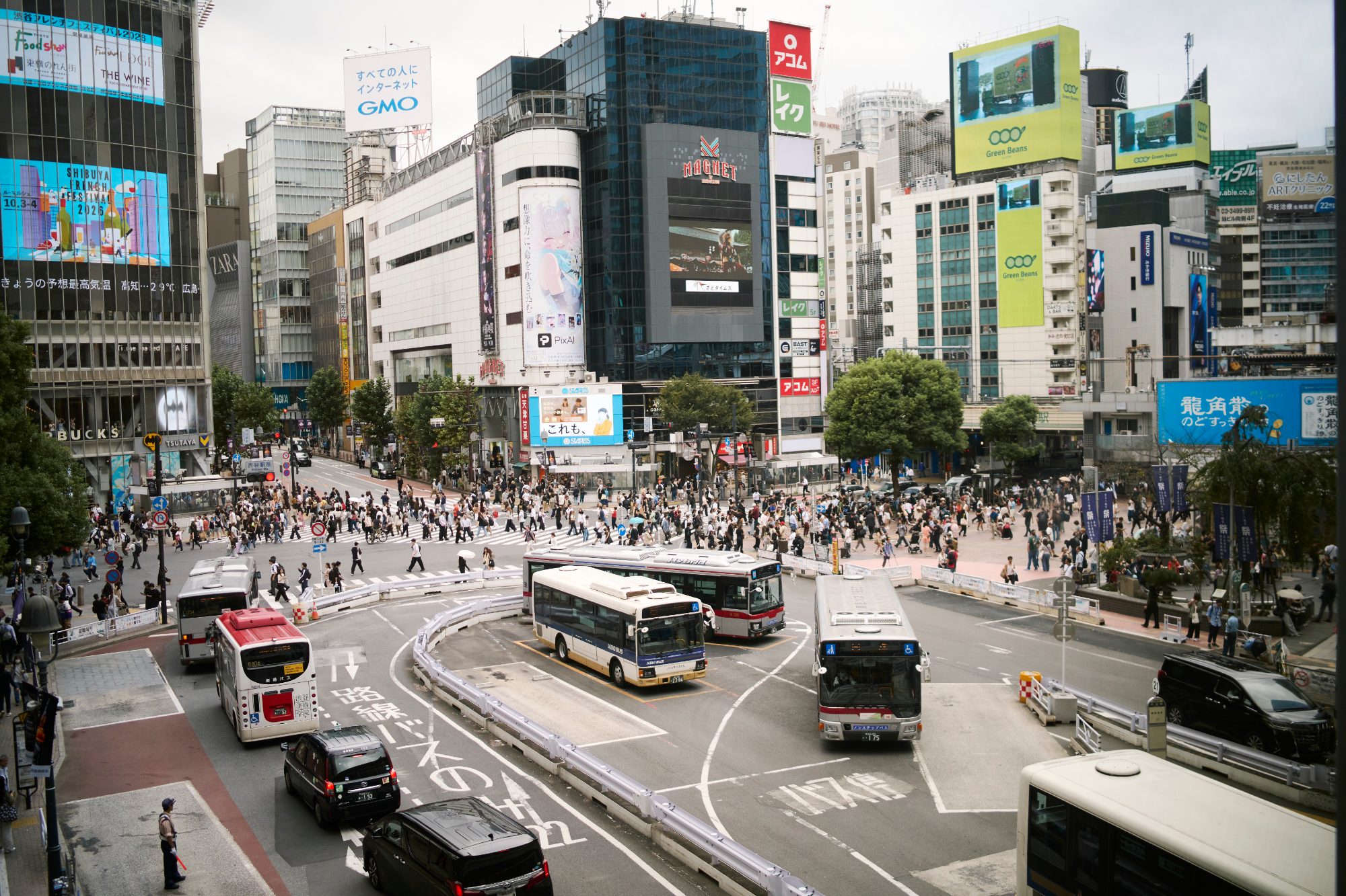 A famous scramble crossing seen from above, buses and crowds below