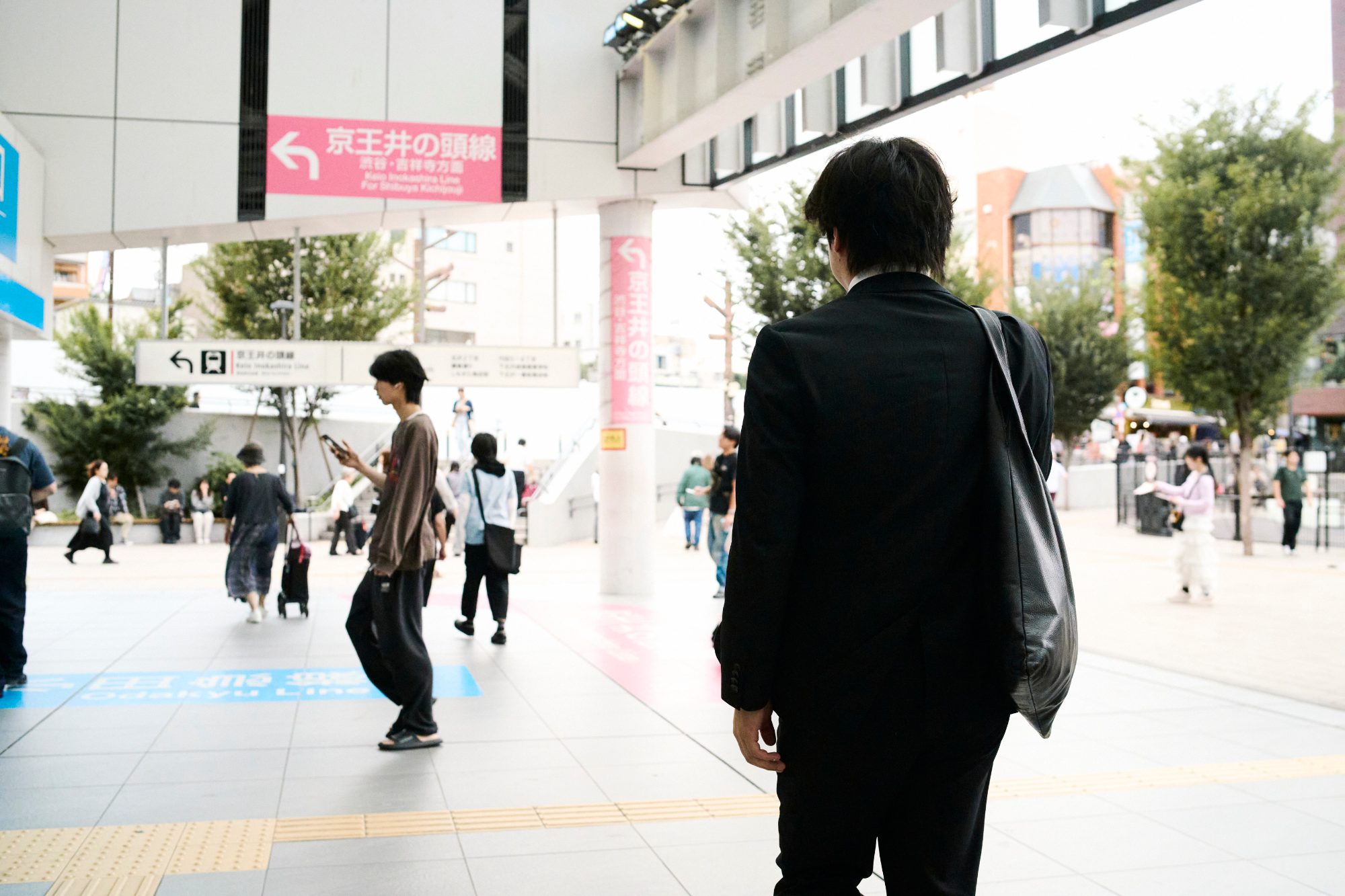 A man in black crossing a wide station plaza