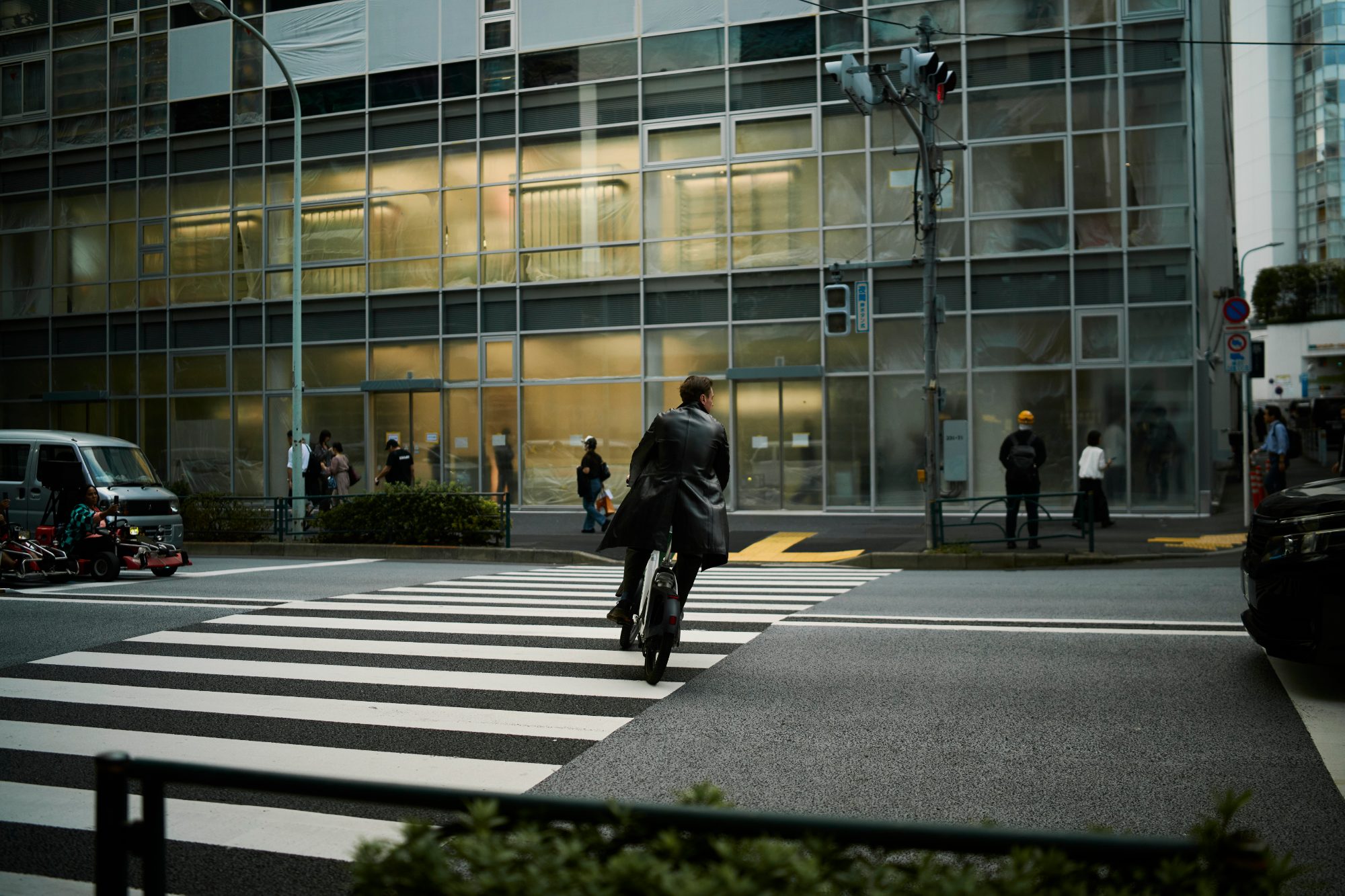 A cyclist crossing in front of a glass office building