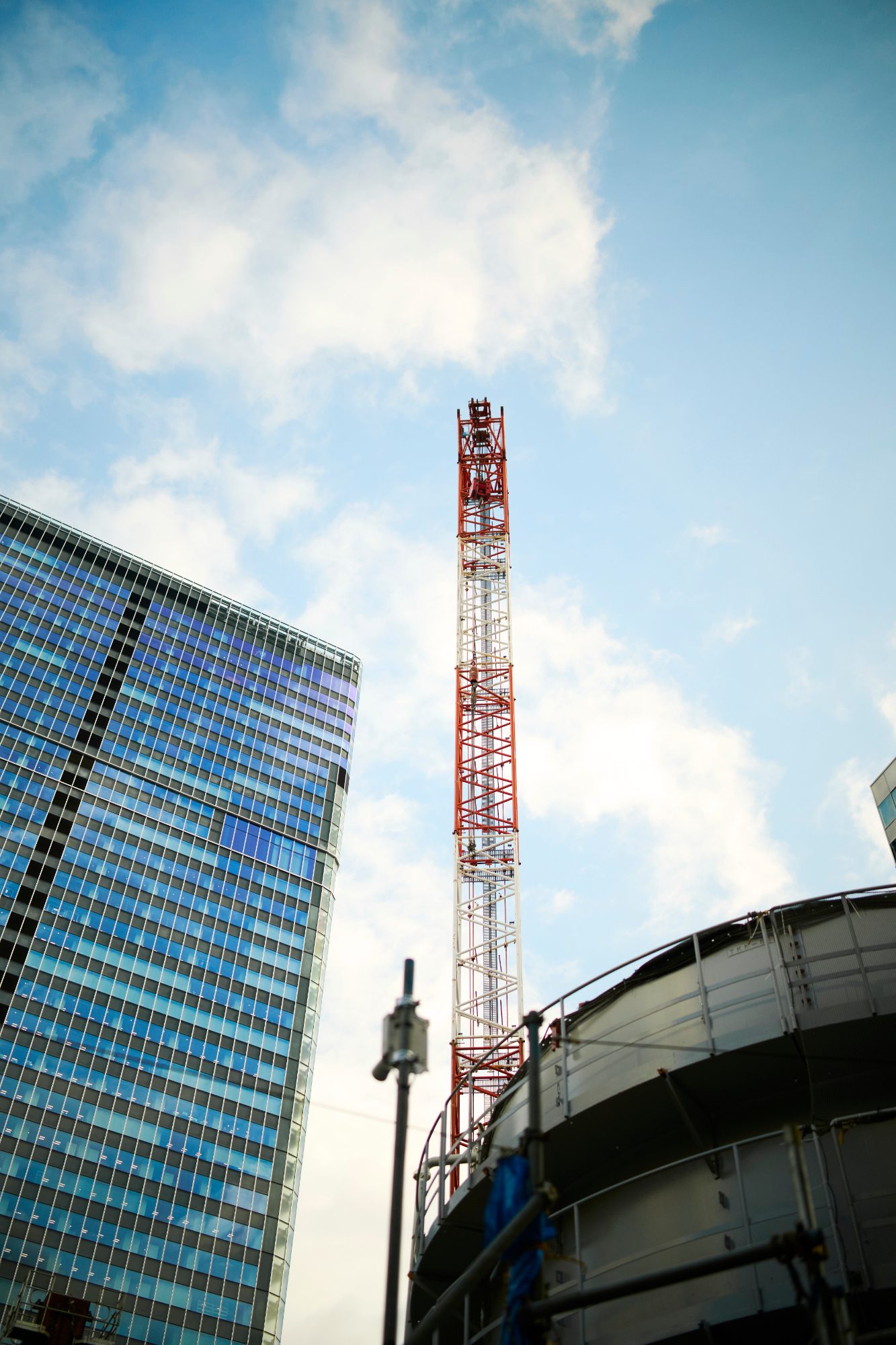 A red crane and a glass tower against blue sky