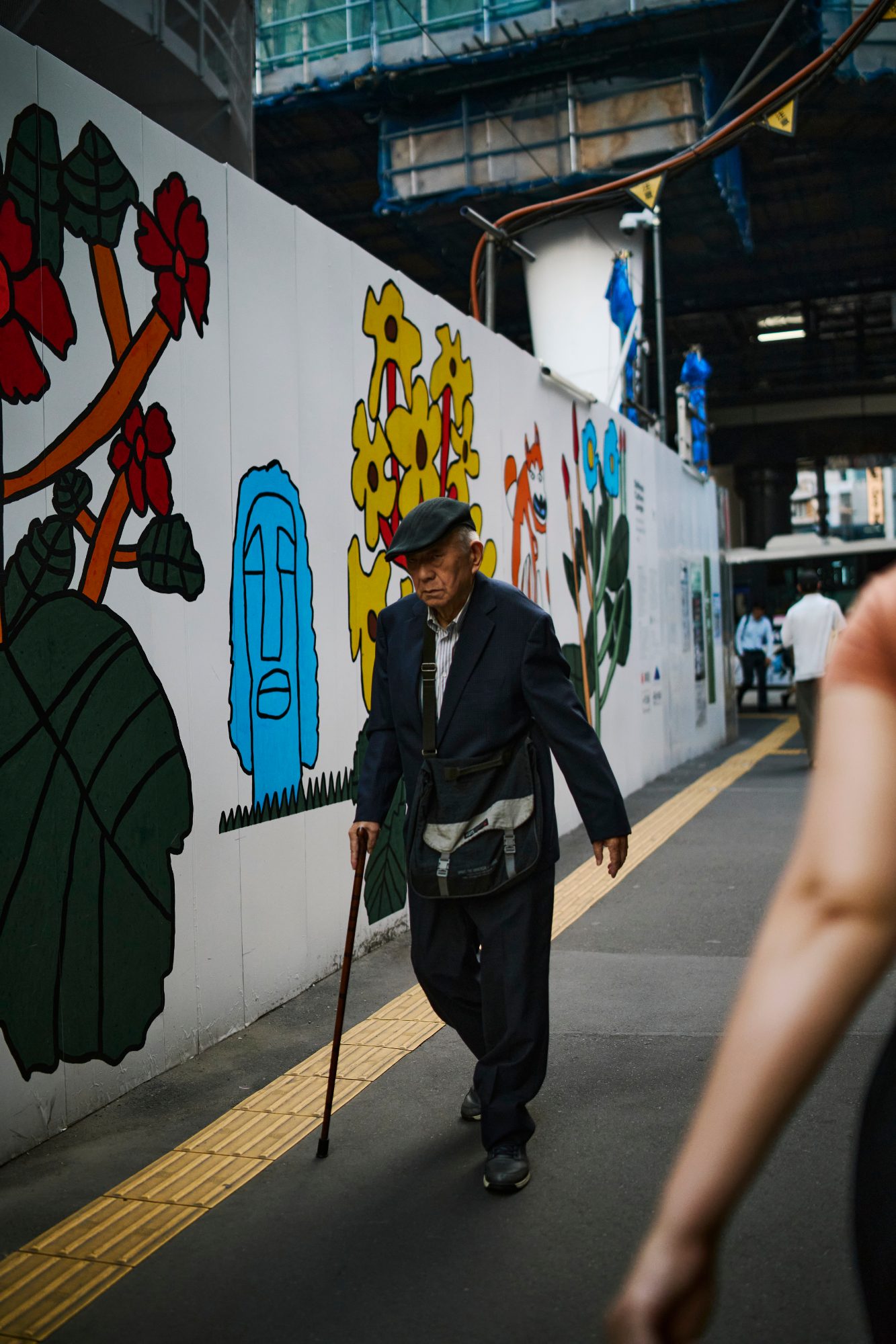 An elderly man walking past a painted mural