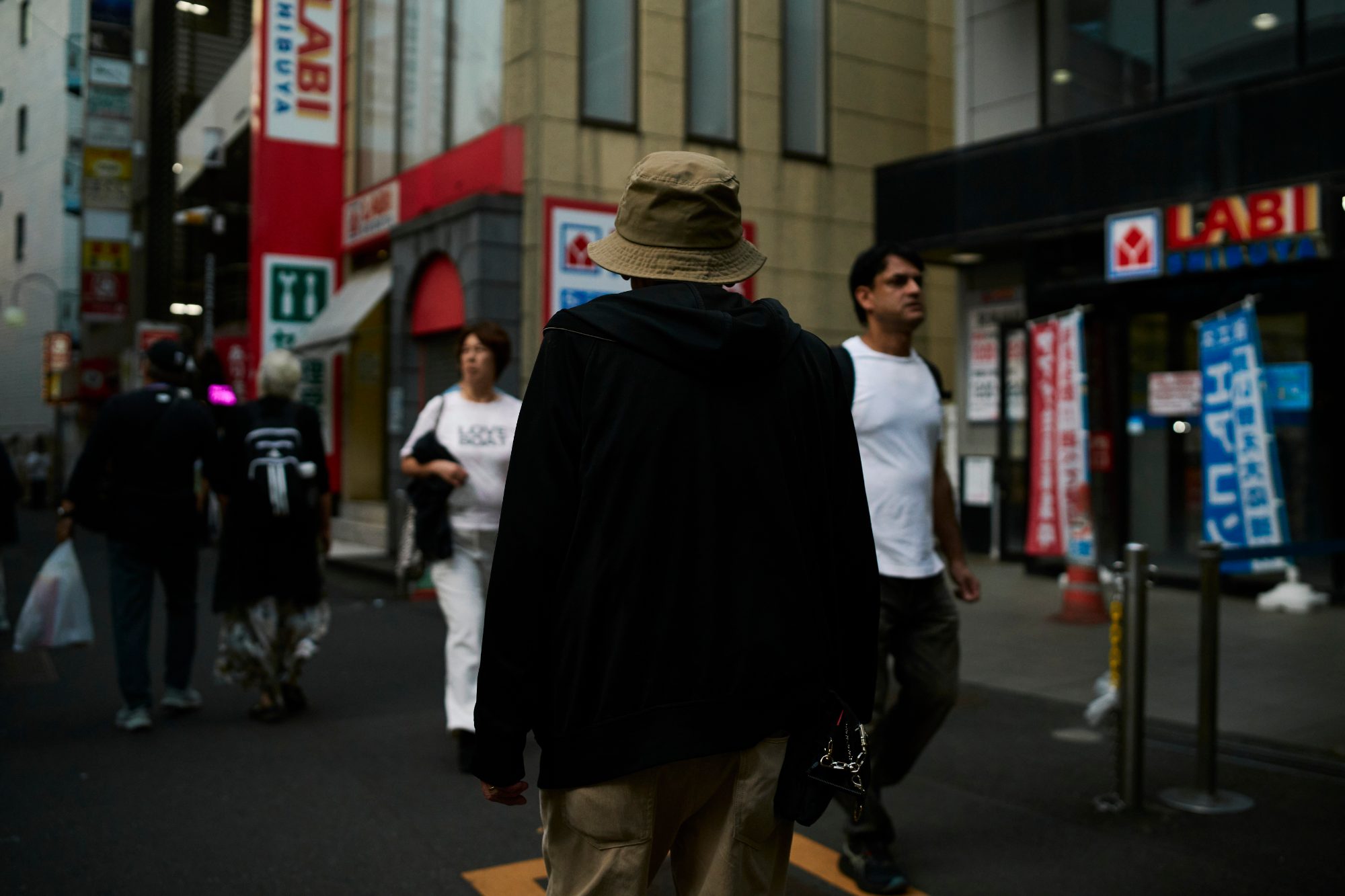 A man in a bucket hat walking through a busy electronics district