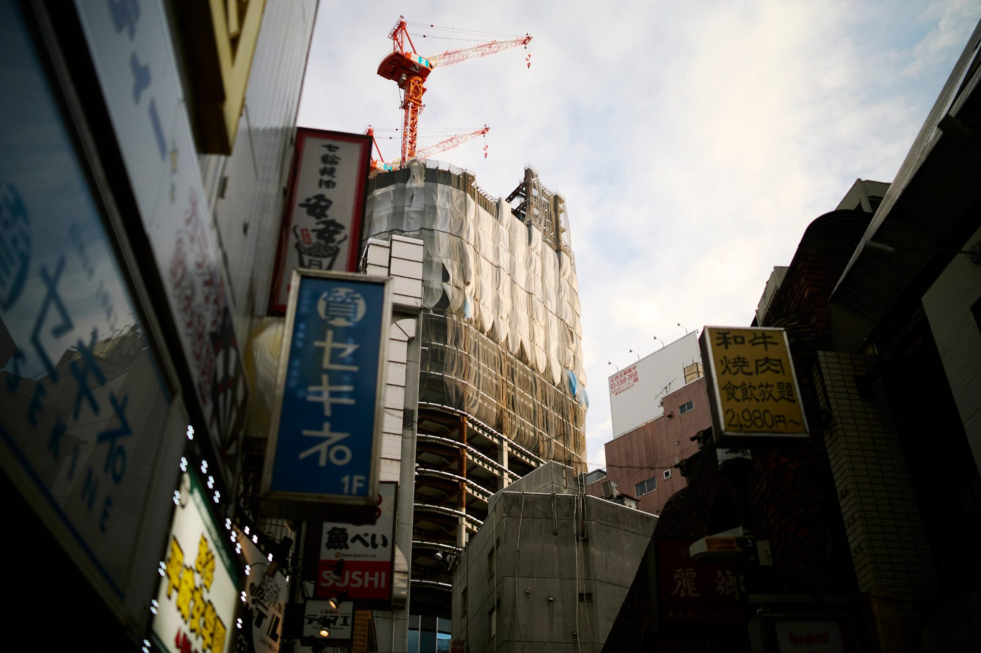 Shop signs and a construction crane against the sky