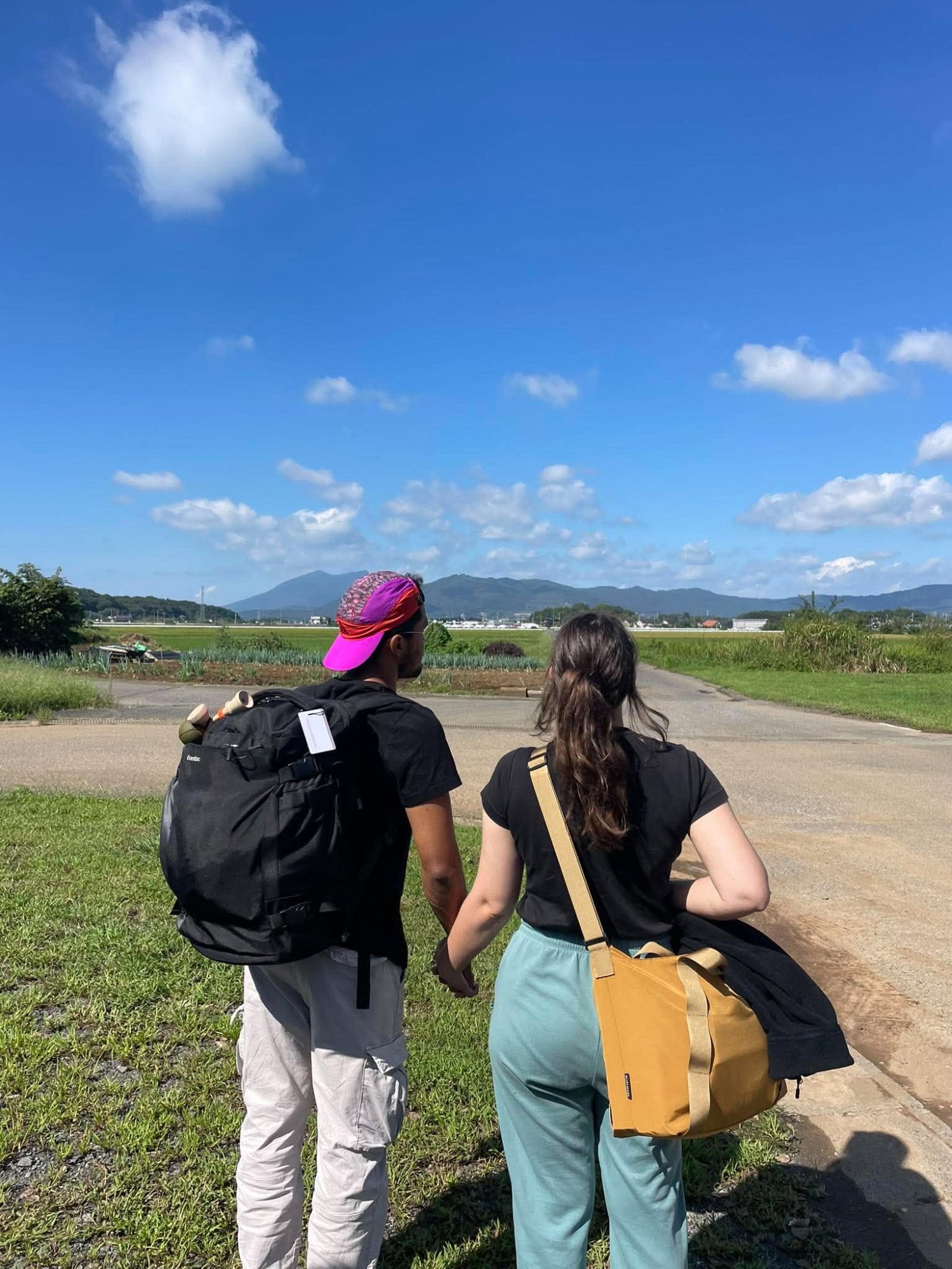 Two people walking a field path under blue sky