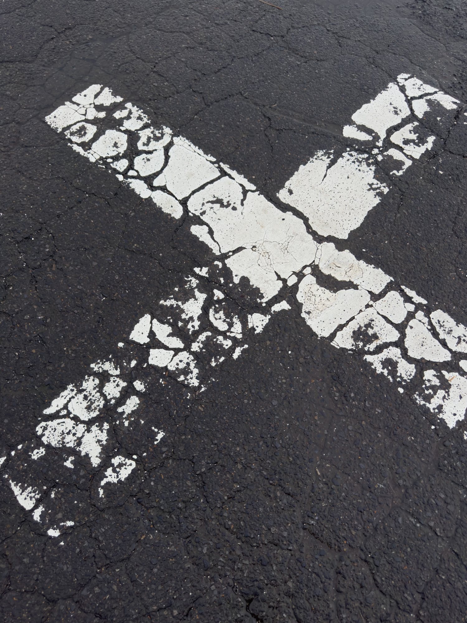 A white X painted on wet asphalt