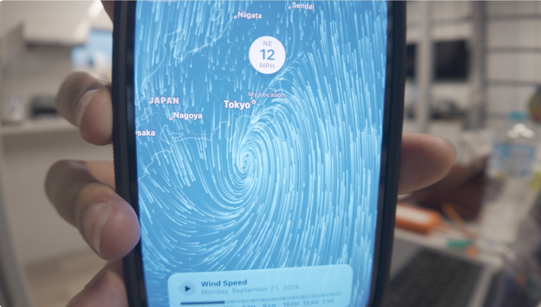 A phone held up showing the typhoon's wind field spiraling toward Tokyo, September 21