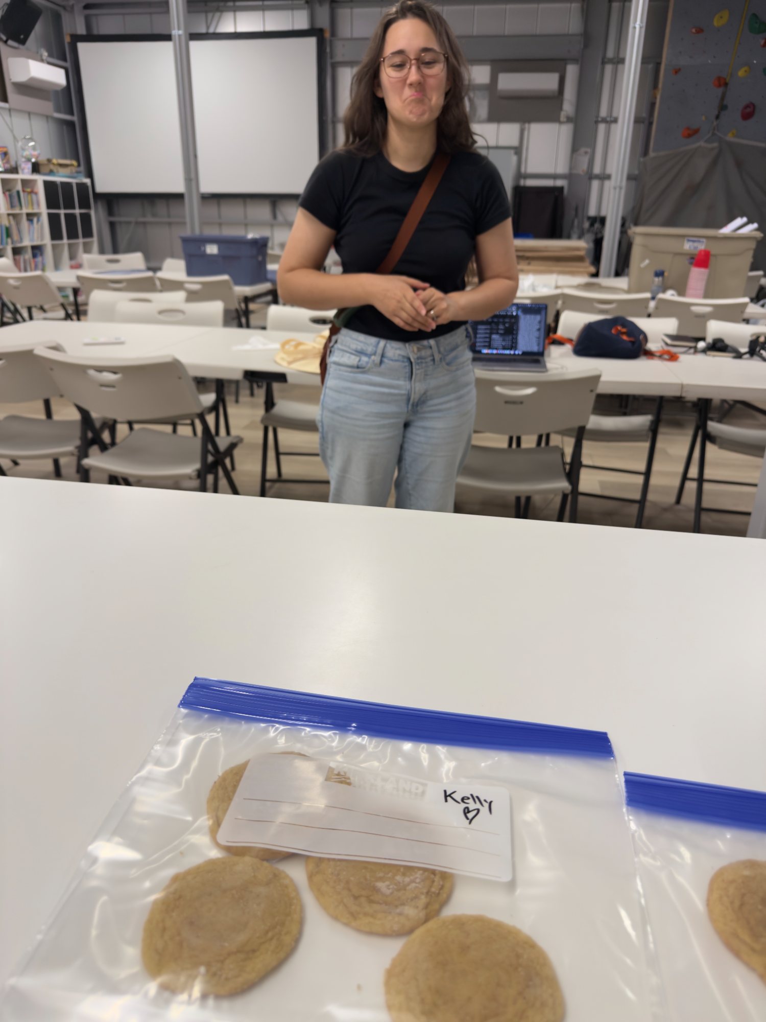Kelly making a teary face behind a bag of homemade cookies labeled with her name