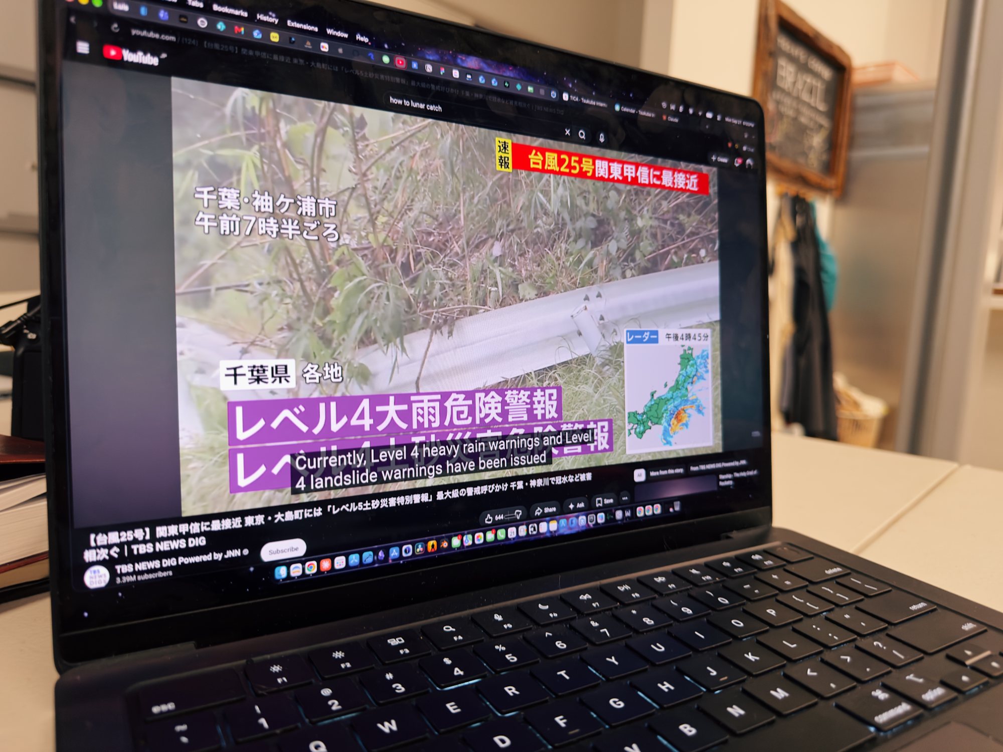 A laptop playing Japanese news coverage of Typhoon 25 with Level 4 heavy rain and landslide warnings