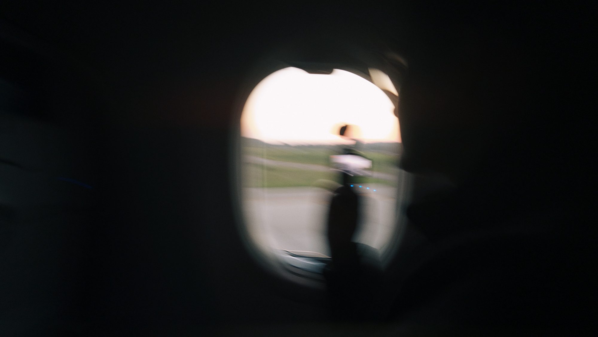 Blurred view through an airplane window at sunrise on the tarmac
