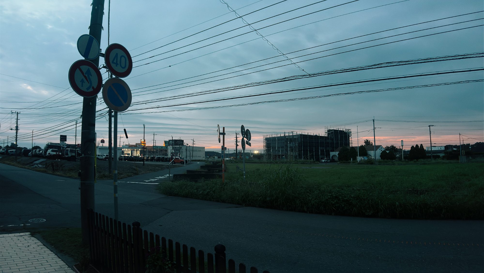 A quiet Japanese street at dusk with road signs and power lines
